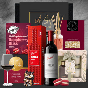 Gourmet gift set with wine, chocolate, and other items on a gray background