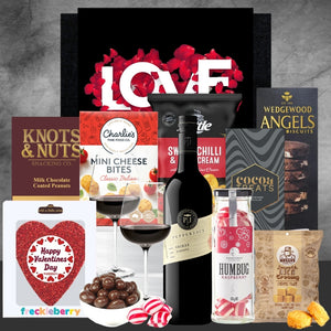 Gourmet gift set with wine, snacks, and confections on a gray background