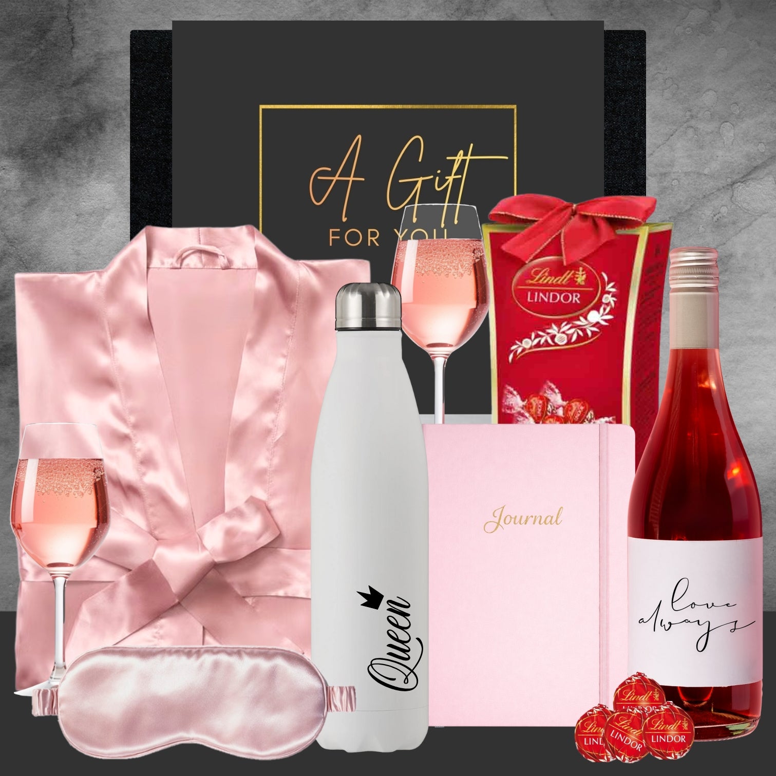 Gourmet gift set with wine, chocolates, and other items on a gray background