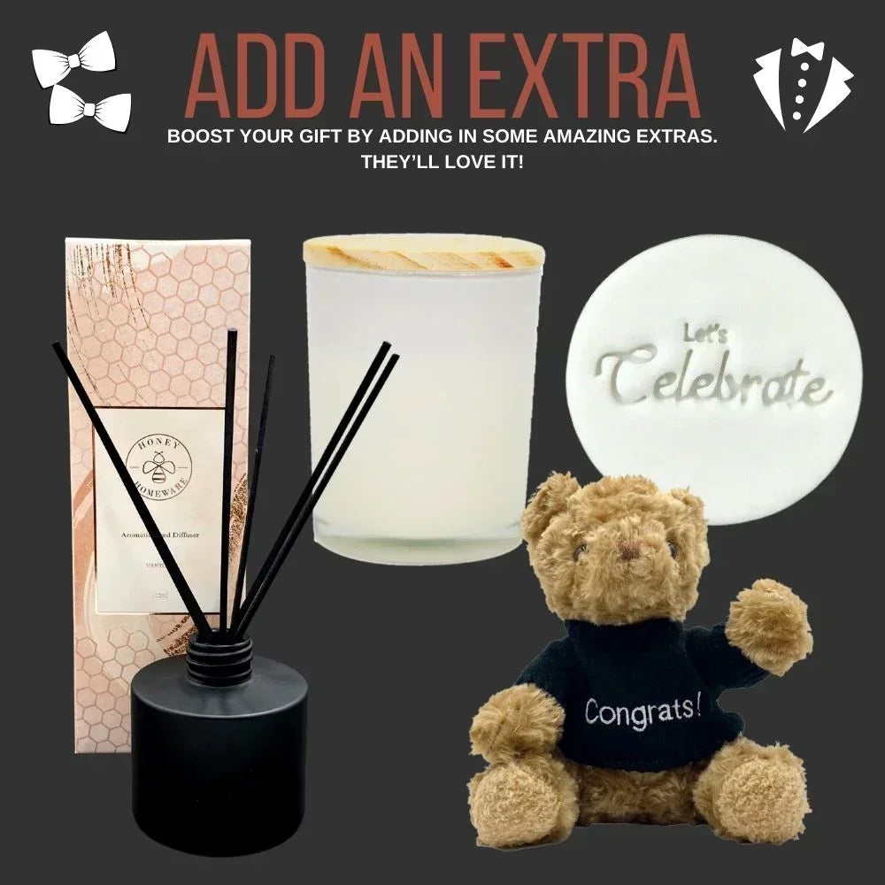 Gift set with diffuser, candle, and teddy bear with 'Congrats!' shirt on a dark background.