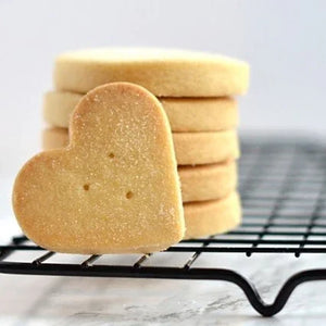 Heart-shaped cookie on a cooling rack with stacked cookies in the background