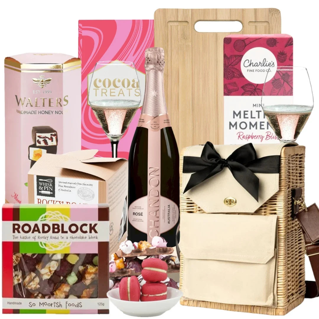 Gift basket with champagne, snacks, and a cutting board on a white background