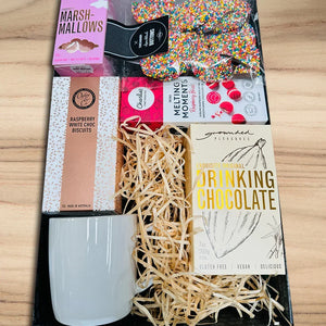 Gift set with drinking chocolate, marshmallows, and other treats on a wooden surface