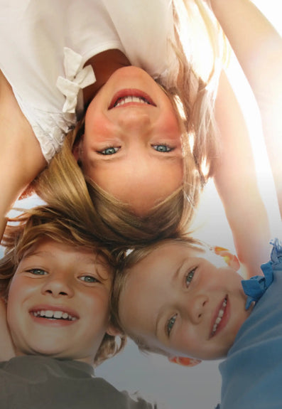 Three children lying on their backs with a plain background