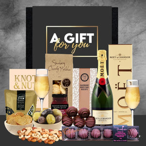 Gift basket with Moët champagne, chocolates, and snacks on a gray background