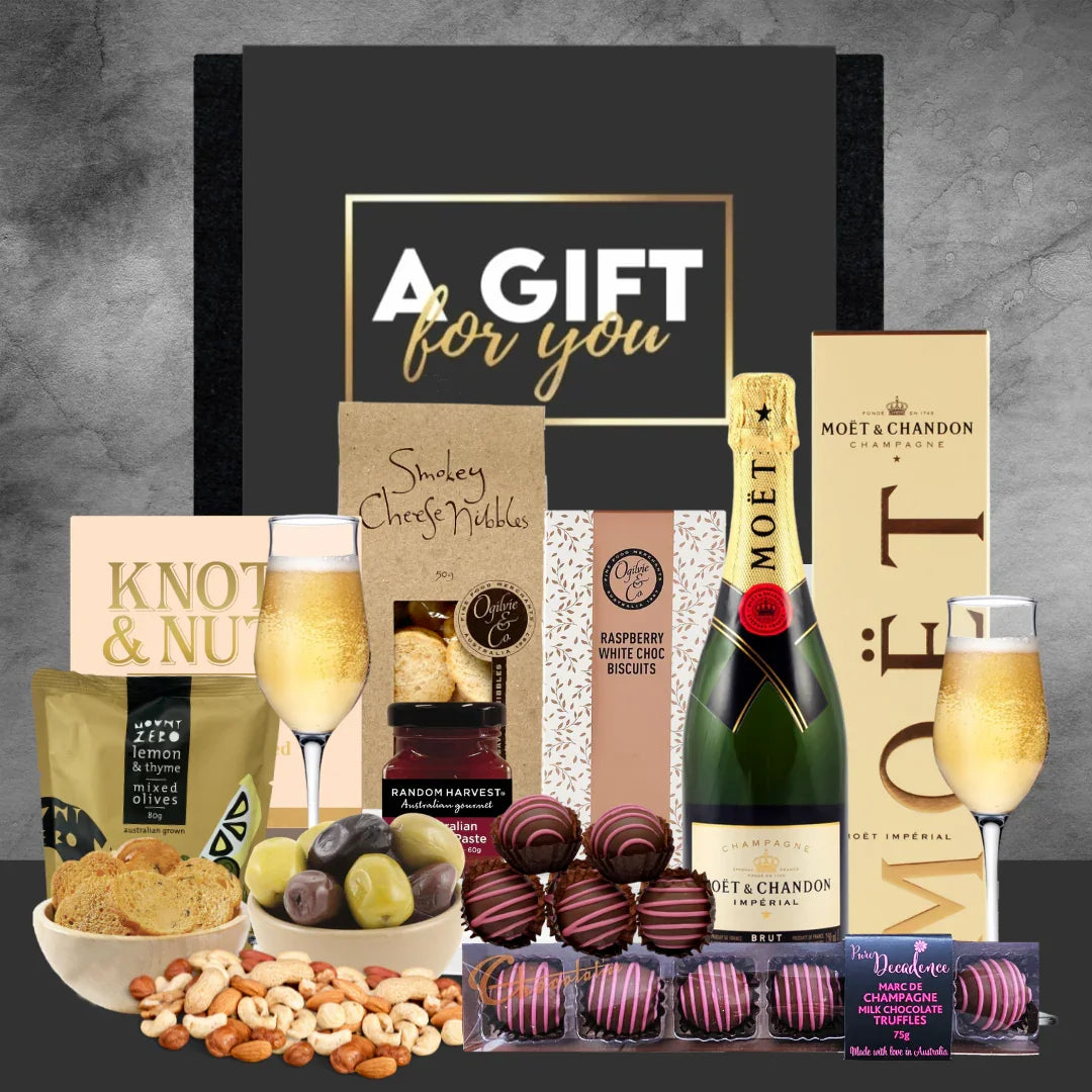 Gift basket with Moët champagne, chocolates, and snacks on a gray background