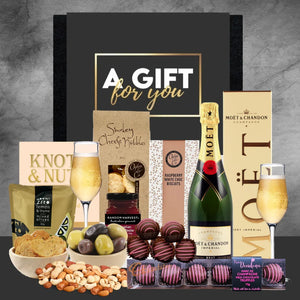 Gift basket with Moët champagne, chocolates, and snacks on a gray background
