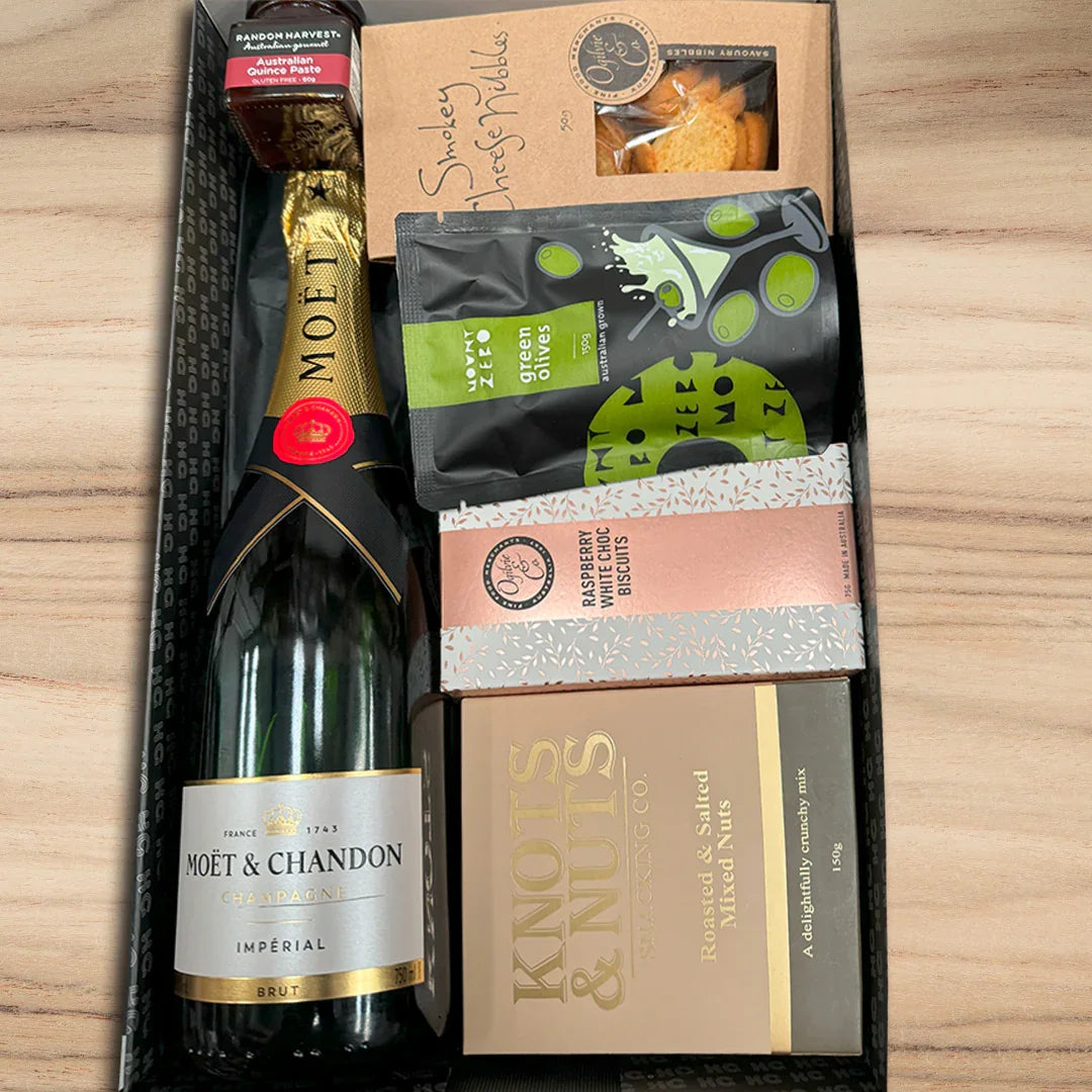 Gift set with Moët & Chandon champagne and assorted snacks on a wooden surface