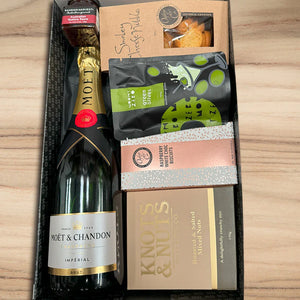 Gift set with Moët & Chandon champagne and assorted snacks on a wooden surface