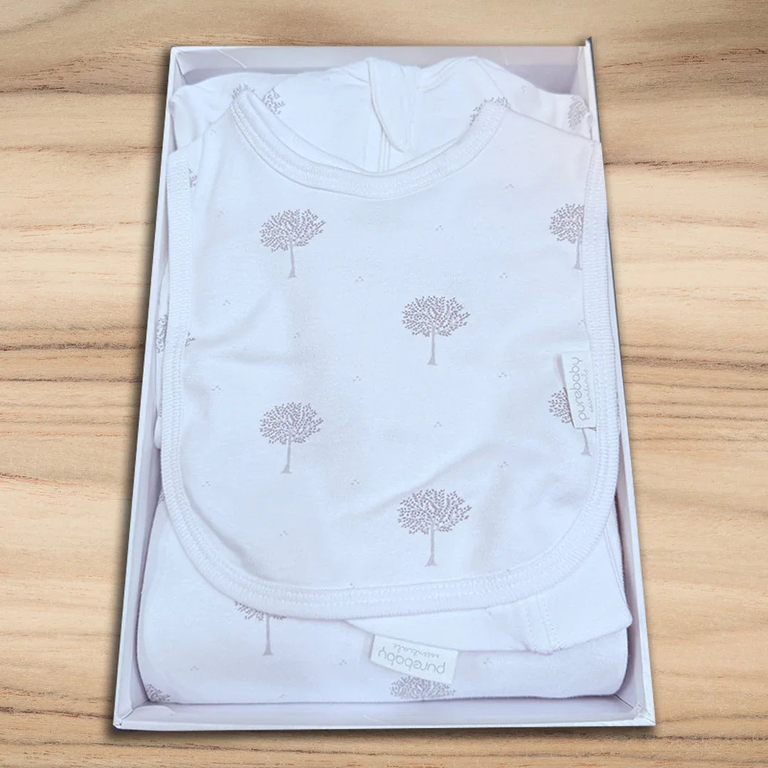 White baby onesie with tree pattern in a box on a wooden surface