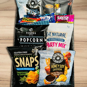 Assorted snack packages including popcorn, honey soy chicken, and party mix on a wooden surface.