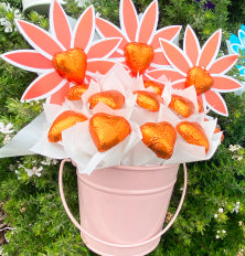 Decorative flowers in a pink bucket with a blurred green background