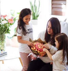 Two women and a child arranging flowers in a living room.
