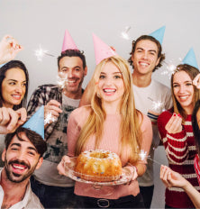 Group of friends celebrating a birthday with cake and drinks.