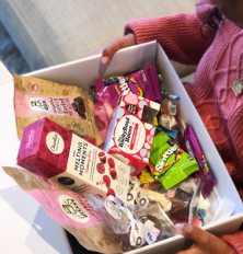 Box of assorted snacks including cookies and bars with visible branding.