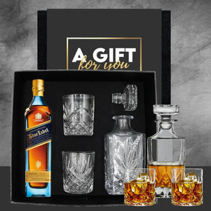 Whiskey gift set with bottle, glasses, and decanter on a gray background