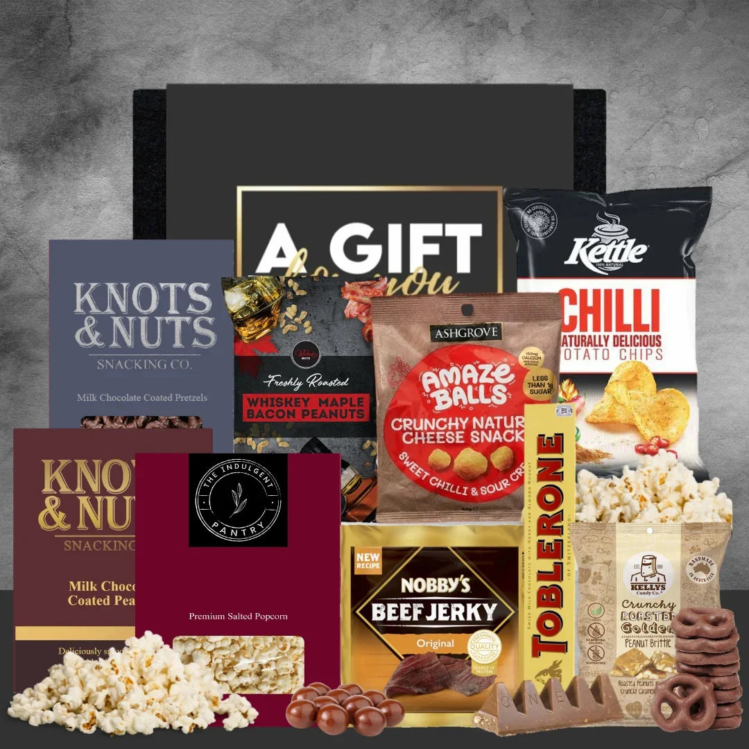 Assorted snack items including popcorn, candy, and packaged snacks on a gray background