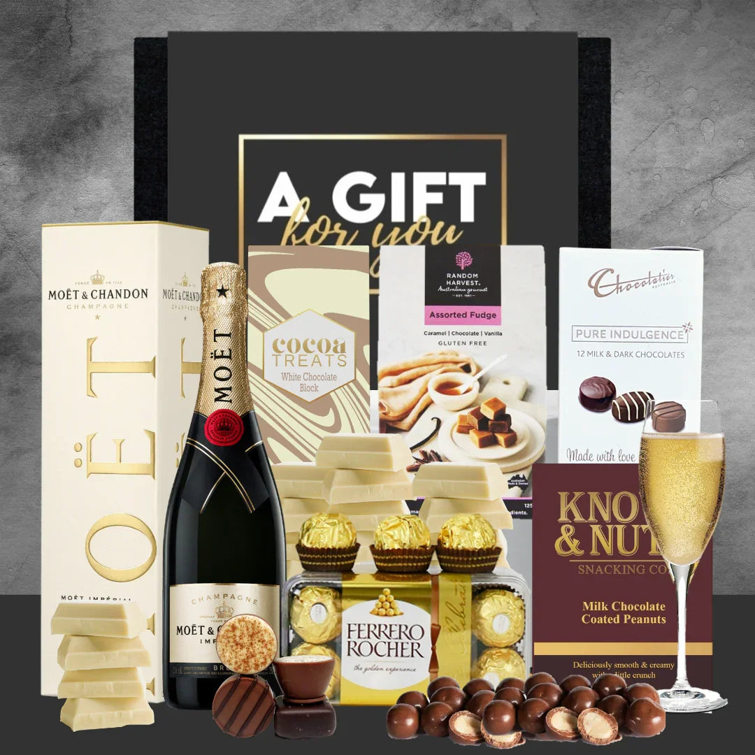 Gift basket with Moët & Chandon champagne, chocolates, and other treats on a gray background.
