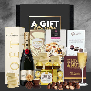 Gift basket with Moët & Chandon champagne, chocolates, and other treats on a gray background.