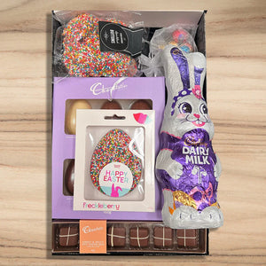 Easter gift set with Cadbury Dairy Milk chocolate bunny and other Easter-themed items on a wooden surface.