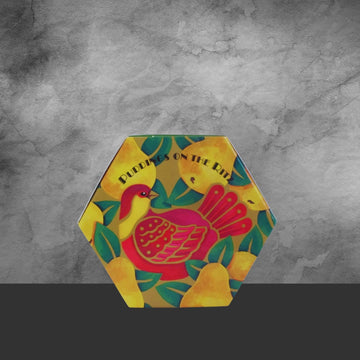 Hexagonal tin of Christmas cake with colorful partridge and pear illustration, labeled Puddings on the Ritz