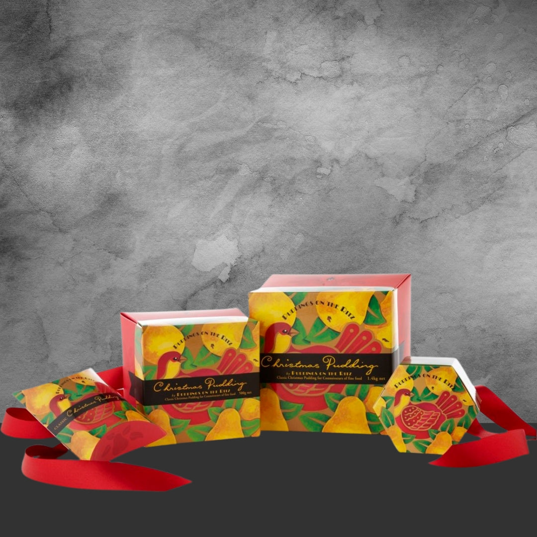 Pack of four colorful Christmas pudding boxes with bird and pear design, red ribbon on gray background
