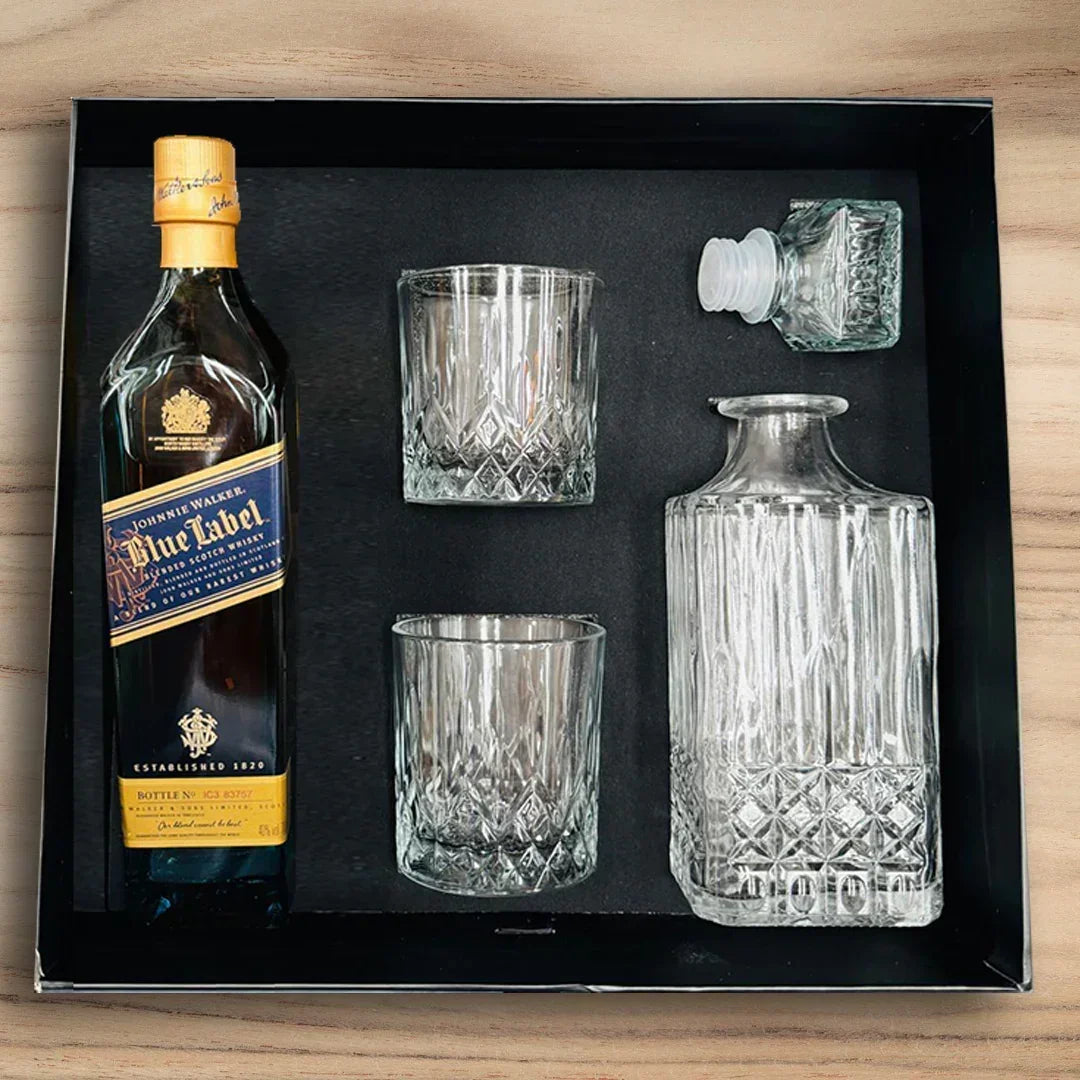 Johnnie Walker Blue Label bottle with glasses and a decanter set in a box on a wooden surface