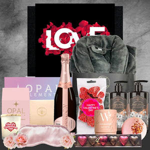 Valentine's Day gift basket with champagne, bath products, and other items on a gray background.
