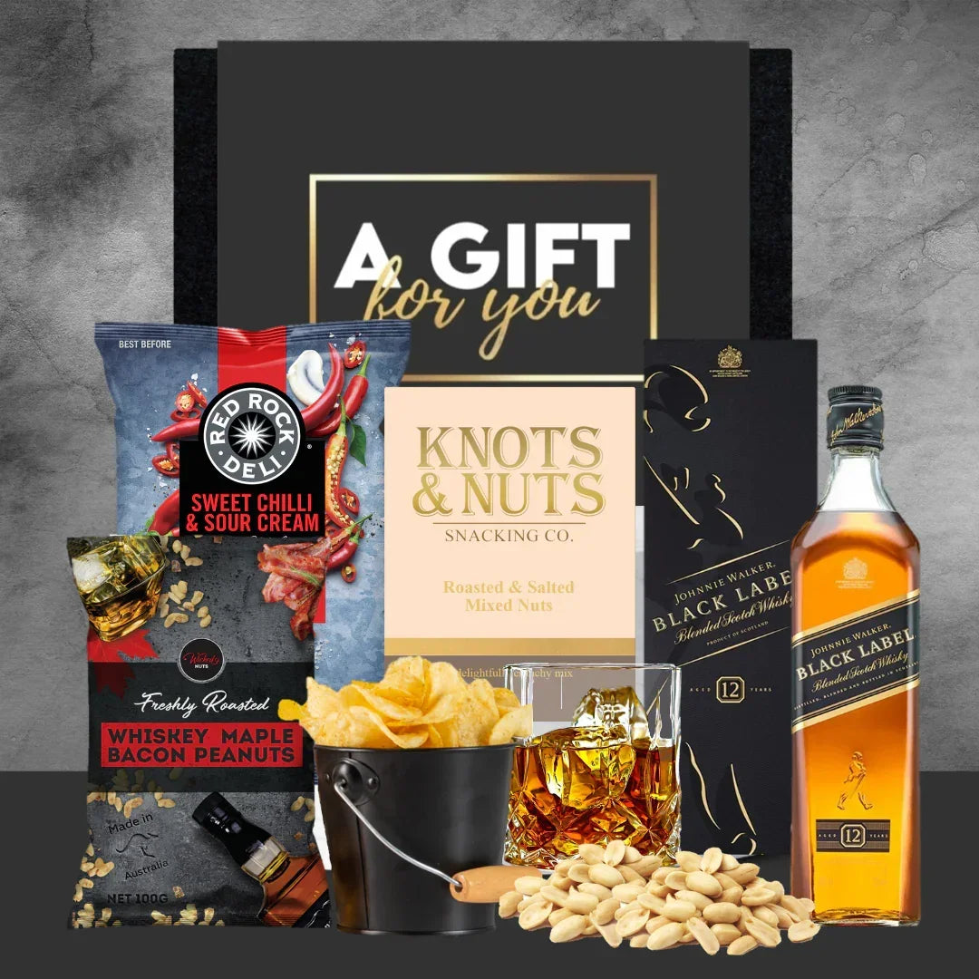 Gift set with snacks and a bottle of Johnnie Walker Black Label whisky on a gray background.