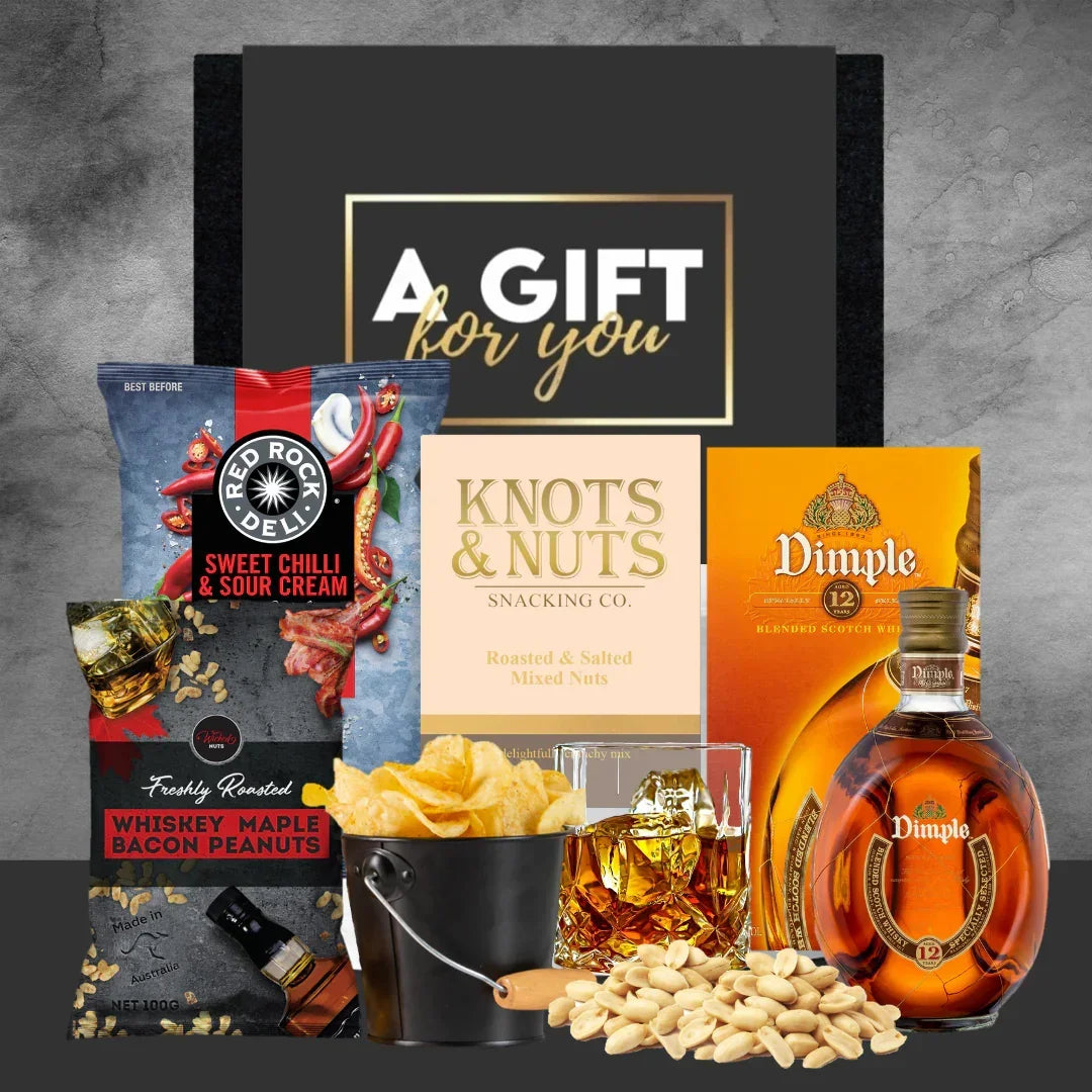 Gift basket with snacks, drinks, and a bottle of Dimple whiskey on a gray background.
