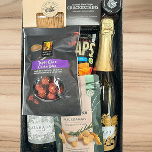 Gift set with wine, snacks, and a bottle of water on a wooden surface