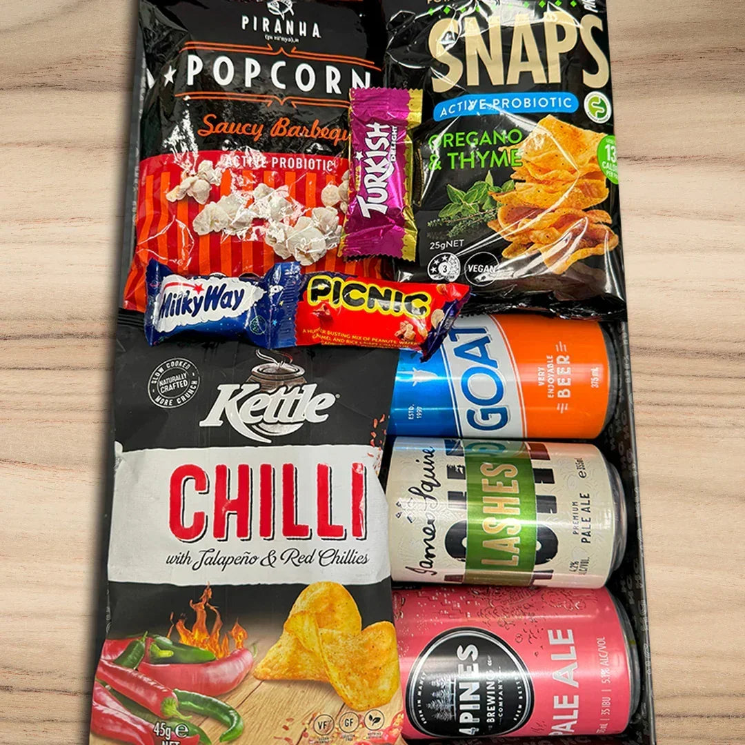Assorted snack items including popcorn, chips, and drinks on a wooden surface