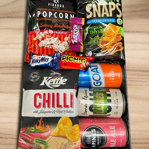 Assorted snack items including popcorn, chips, and drinks on a wooden surface
