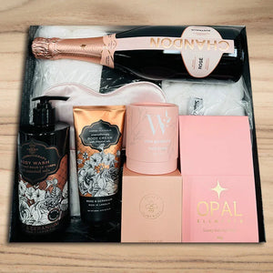 Christmas Gift set with champagne, body care products, and Opal Elements packaging on a wooden surface.