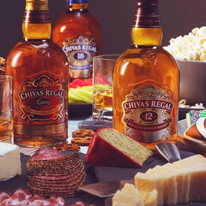 Chivas Regal whiskey bottles with snacks on a table