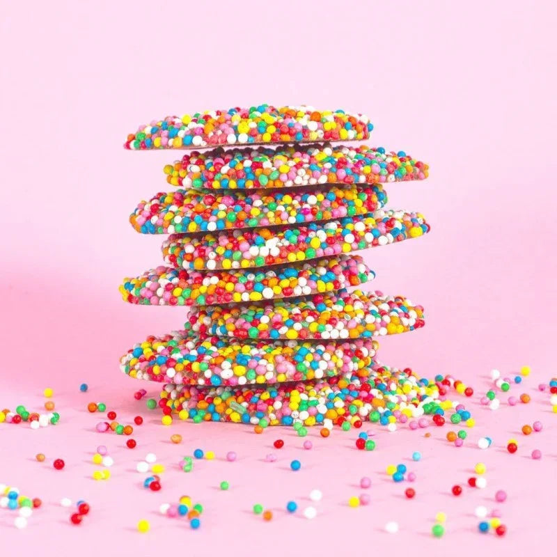 Stack of colorful cookies with sprinkles on a pink background
