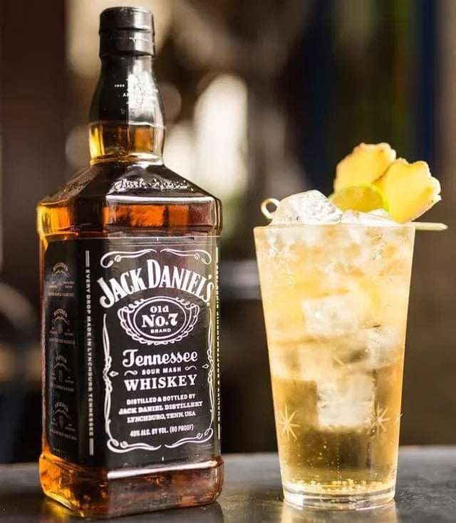 Jack Daniel's whiskey bottle with a cocktail garnished with pineapple on a blurred background