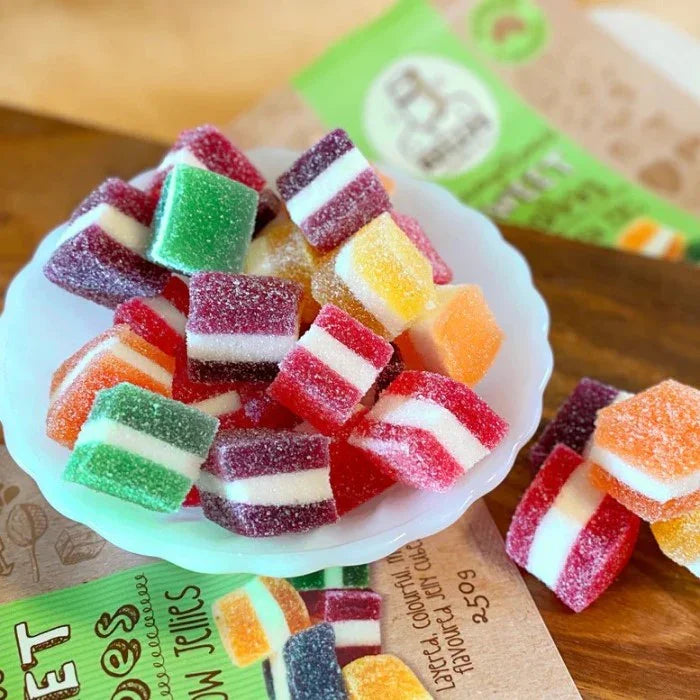 Colorful jelly candies in a white dish with a box of jelly beans in the background.