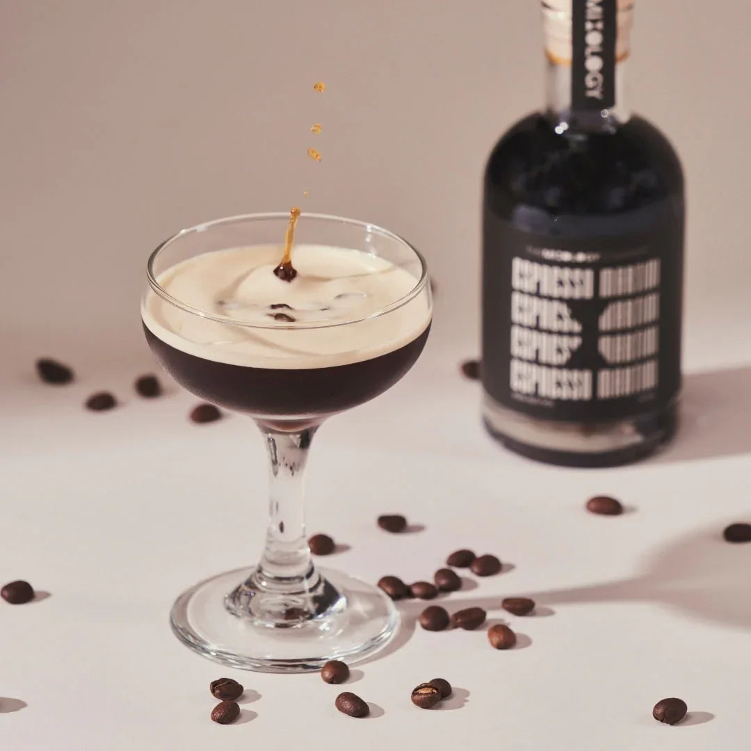 Cocktail in a glass with a bottle of coffee liqueur and scattered coffee beans on a light background