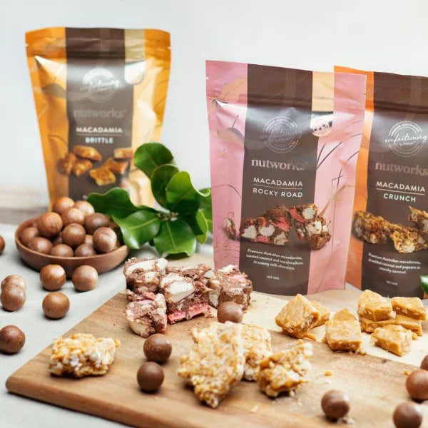 Nutworks macadamia snacks on a wooden board with packaging in the background