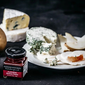 Jar of Random Harvest Australian Quince Paste on a cheese platter with assorted cheeses and pears.