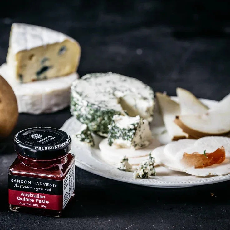 Jar of Random Harvest Australian Quince Paste on a cheese platter with assorted cheeses and pears.
