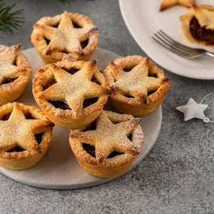 Star-shaped mince pies on a plate with a fork and plate in the background.